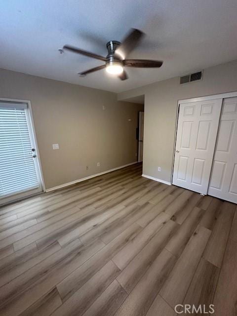 interior space featuring a ceiling fan, visible vents, wood finished floors, baseboards, and a closet