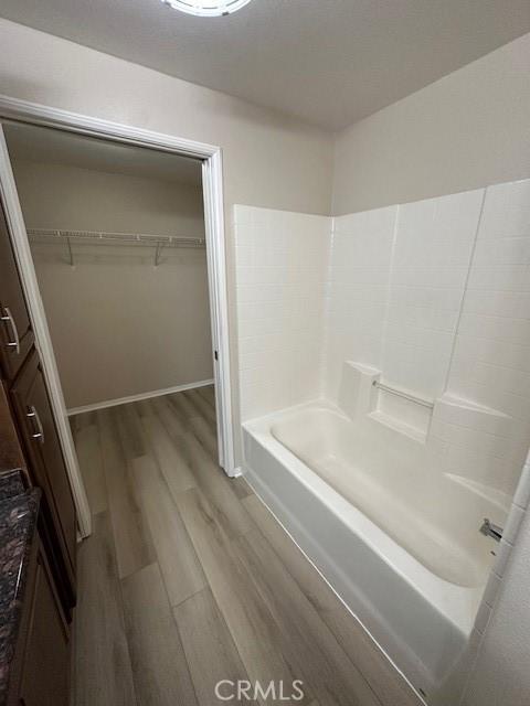 full bath featuring baseboards, wood finished floors, and a spacious closet