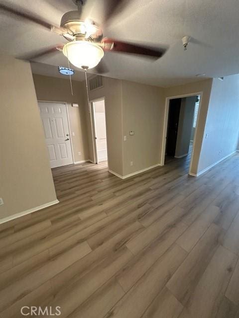 unfurnished room with baseboards, ceiling fan, and wood finished floors