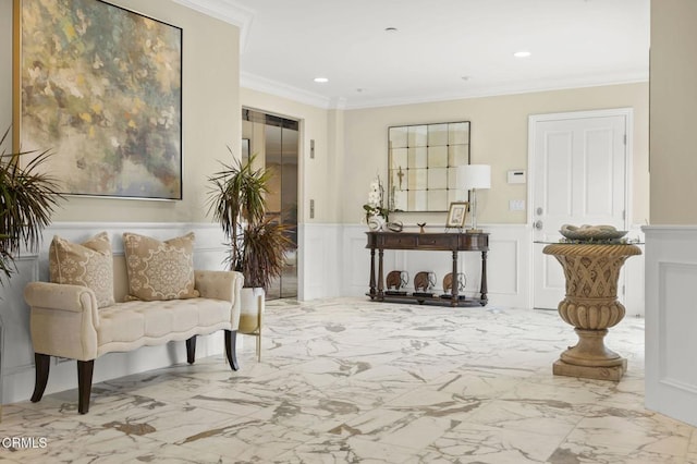 living area featuring marble finish floor, ornamental molding, a decorative wall, and a wainscoted wall