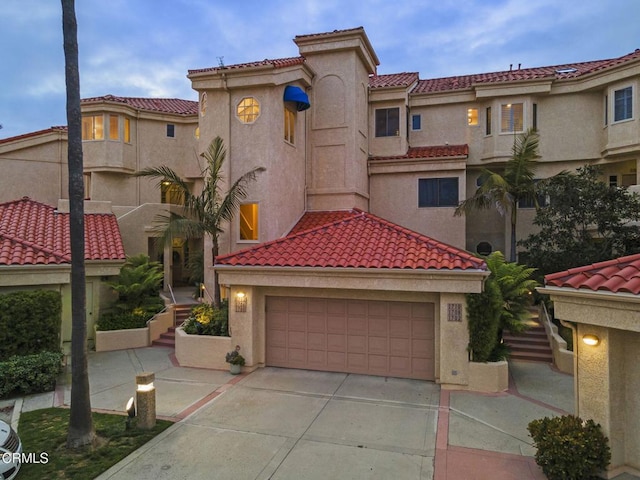mediterranean / spanish house featuring concrete driveway, a tiled roof, and stucco siding