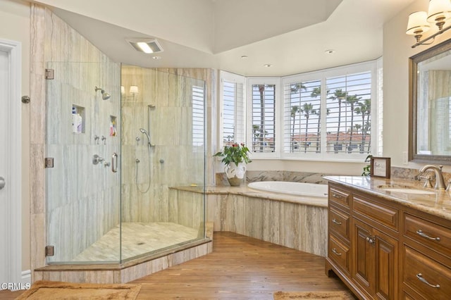bathroom with a shower stall, a garden tub, vanity, and wood finished floors