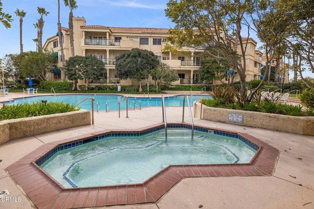 community pool featuring a patio area and a hot tub