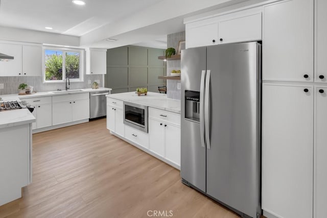 413 N Rimhurst Ave, Covina, CA 91724 - kitchen featuring white cabinetry, tasteful backsplash, a sink, light wood finished floors, and appliances with stainless steel finishes