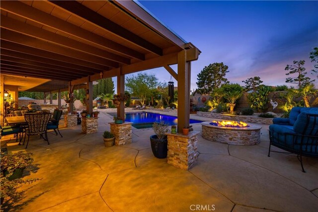 patio terrace at dusk with an outdoor living space with a fire pit and an outdoor pool