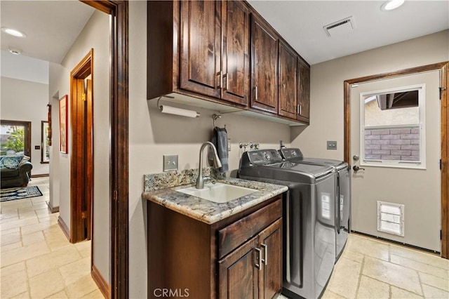 clothes washing area featuring stone tile floors, visible vents, a sink, and cabinet space