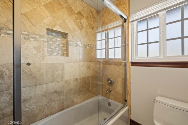 full bath with bath / shower combo with glass door, a wealth of natural light, and toilet