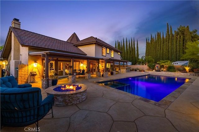 pool at dusk featuring an outdoor pool, a patio area, and an outdoor living space with a fire pit