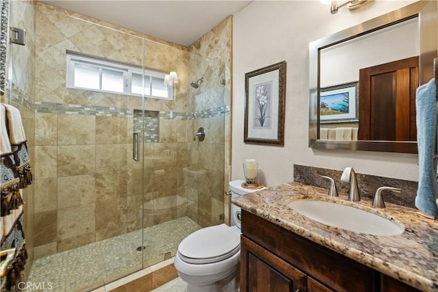 bathroom featuring toilet, a shower stall, and vanity