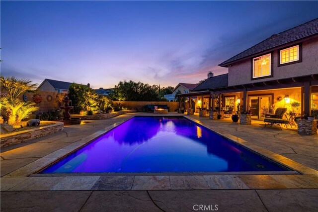 pool at dusk with a patio, a fenced in pool, and a fenced backyard