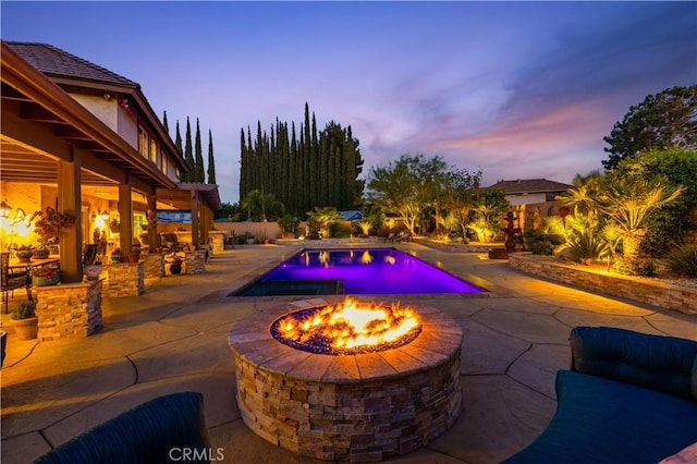 pool at dusk with a patio, an outdoor fire pit, and an outdoor pool