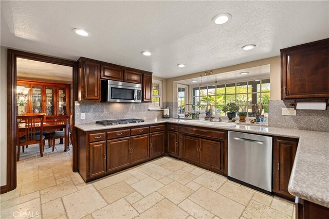 kitchen with light countertops, stone tile floors, appliances with stainless steel finishes, and decorative backsplash