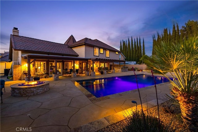 outdoor pool featuring a patio, an outdoor fire pit, and fence