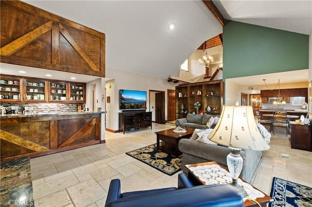 living area featuring stone tile floors, beam ceiling, a chandelier, and high vaulted ceiling