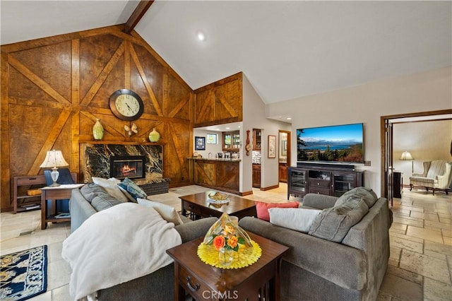 living area with a high end fireplace, high vaulted ceiling, beamed ceiling, recessed lighting, and stone tile floors