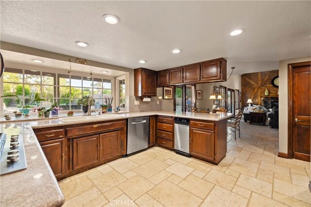 kitchen with stainless steel dishwasher, a sink, light countertops, a peninsula, and recessed lighting