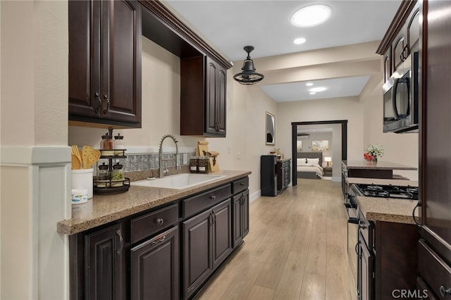 405 E Colton Ave, Redlands, CA 92374 - kitchen with dark brown cabinetry, stainless steel fridge, light countertops, a sink, and light wood finished floors