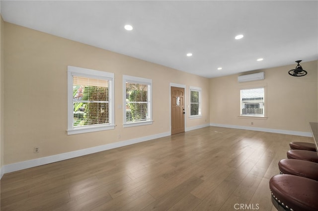 405 E Colton Ave, Redlands, CA 92374 - unfurnished living room featuring a healthy amount of sunlight, baseboards, a wall mounted air conditioner, and wood finished floors
