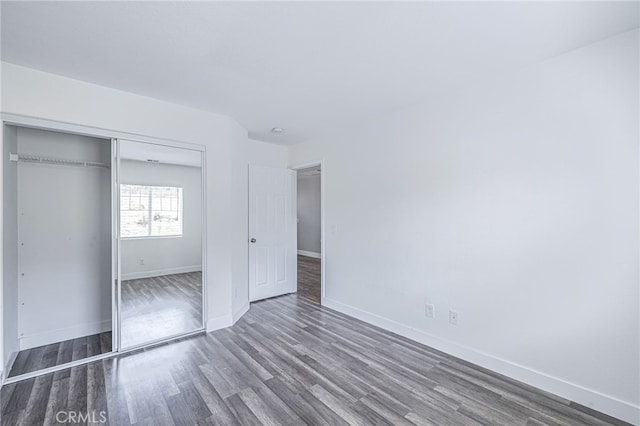 unfurnished bedroom with baseboards, a closet, and wood finished floors