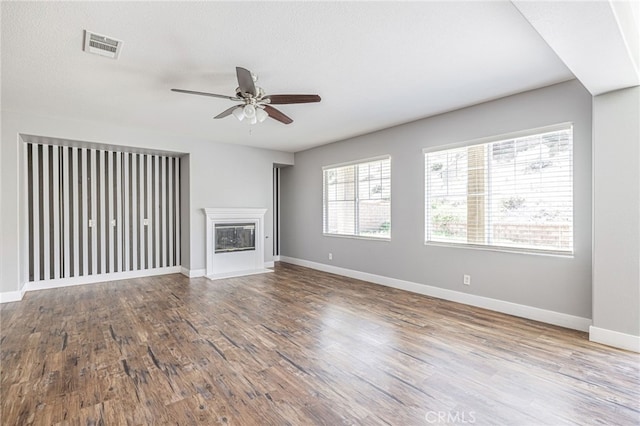 unfurnished living room featuring baseboards, a ceiling fan, and wood finished floors