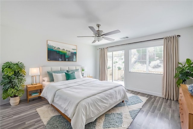 bedroom featuring visible vents, wood finished floors, baseboards, access to outside, and a ceiling fan