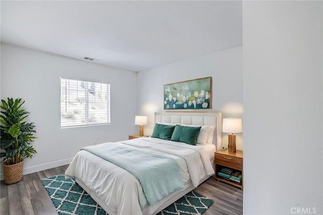 bedroom with baseboards, visible vents, and wood finished floors