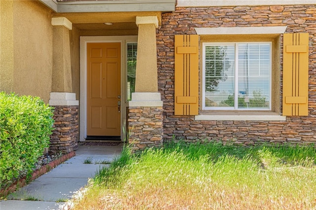 doorway to property featuring stucco siding and stone siding