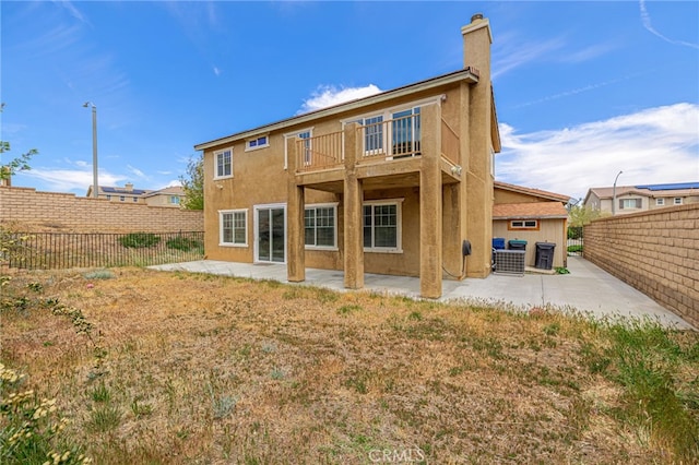 rear view of house featuring a patio, a fenced backyard, stucco siding, and a balcony