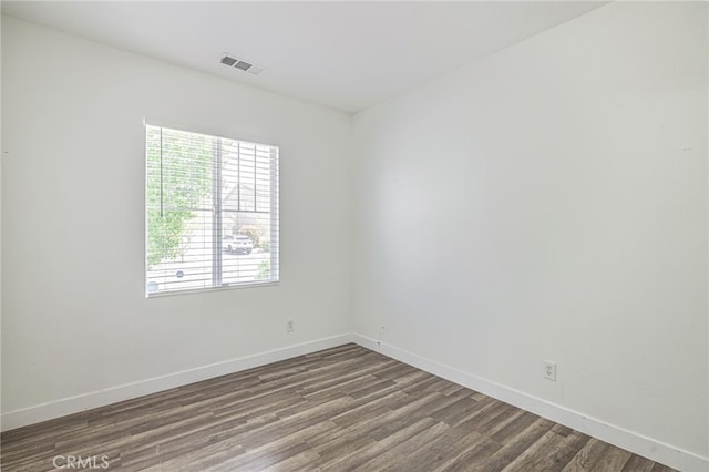 unfurnished room with baseboards, dark wood finished floors, and a healthy amount of sunlight