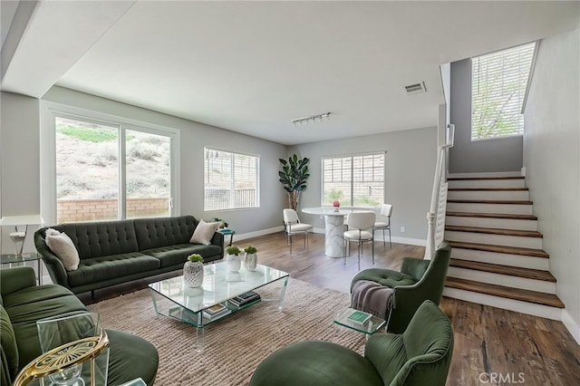 living area with stairway, baseboards, wood finished floors, and visible vents