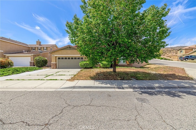 view of front of property featuring concrete driveway, an attached garage, and stucco siding
