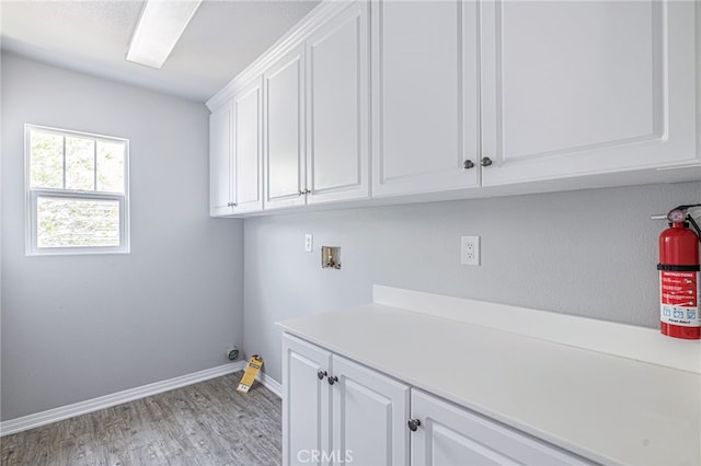 washroom with baseboards, hookup for a washing machine, cabinet space, and light wood finished floors
