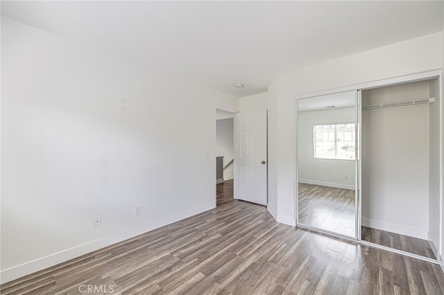 unfurnished bedroom with a closet, baseboards, and wood finished floors
