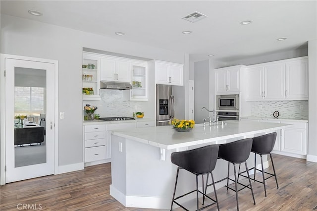 kitchen featuring visible vents, appliances with stainless steel finishes, tasteful backsplash, dark wood finished floors, and under cabinet range hood