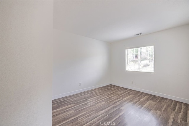 empty room with baseboards, wood finished floors, and visible vents