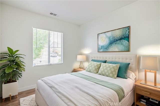 bedroom featuring baseboards, wood finished floors, and visible vents