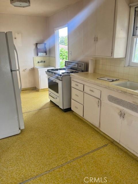 5548 Carley Ave, Whittier, CA 90601 - kitchen with gas range oven, freestanding refrigerator, light countertops, and plenty of natural light