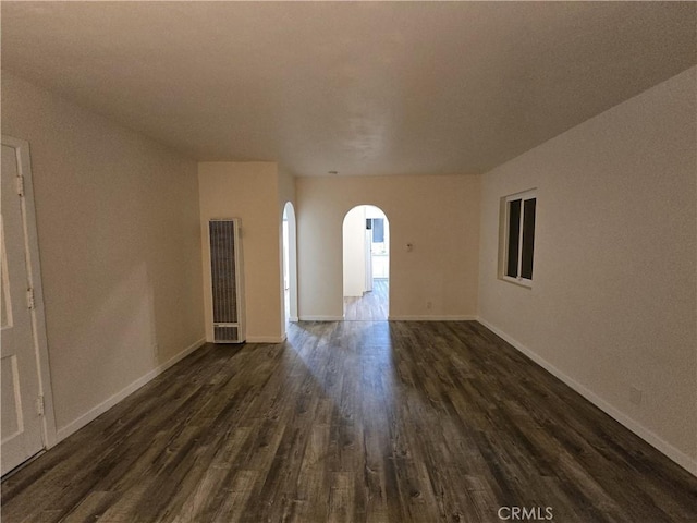 9412 Haney St, Pico Rivera, CA 90660 - empty room with a heating unit, arched walkways, dark wood-style flooring, and baseboards