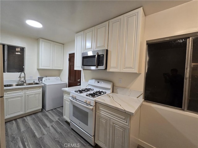 9412 Haney St, Pico Rivera, CA 90660 - kitchen with white gas stove, washer / dryer, stainless steel microwave, a sink, and light wood-style floors