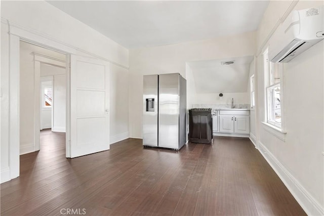 kitchen featuring dark wood-style flooring, light countertops, stainless steel fridge with ice dispenser, a sink, and an AC wall unit