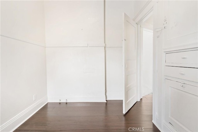 unfurnished room with baseboards and dark wood finished floors