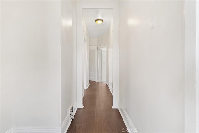 hallway featuring baseboards and dark wood-style floors