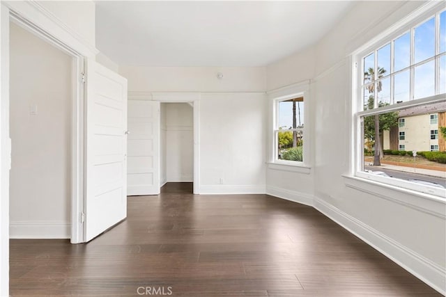 empty room with baseboards and dark wood-style floors