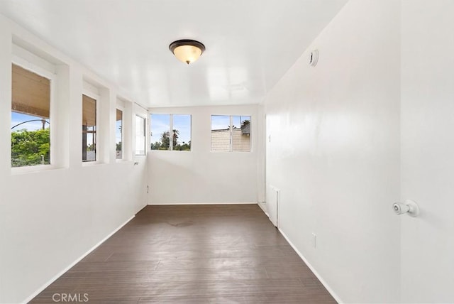 empty room featuring baseboards, plenty of natural light, and wood finished floors