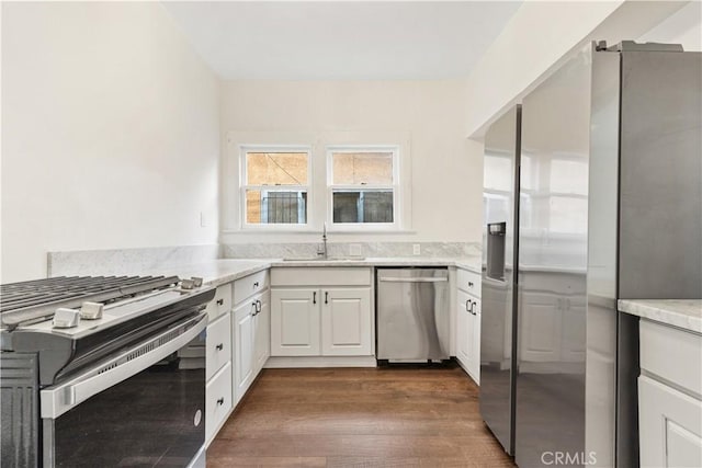 kitchen with a sink, white cabinetry, appliances with stainless steel finishes, and dark wood finished floors