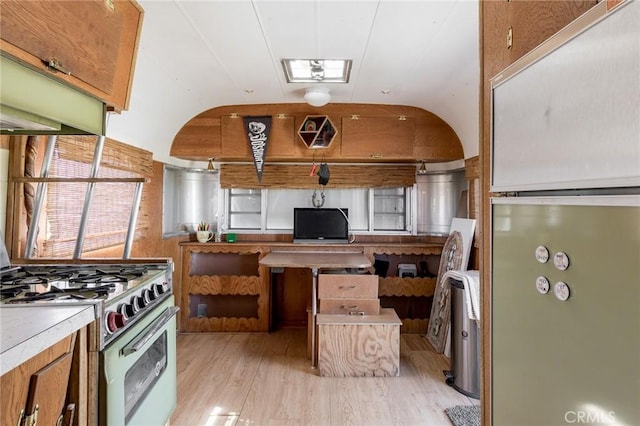 kitchen with refrigerator, open floor plan, light countertops, white range with gas cooktop, and light wood-style flooring