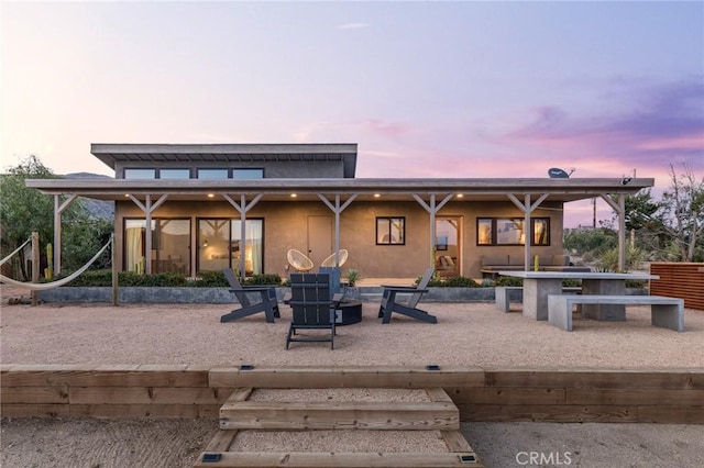 back of property at dusk with a patio and stucco siding
