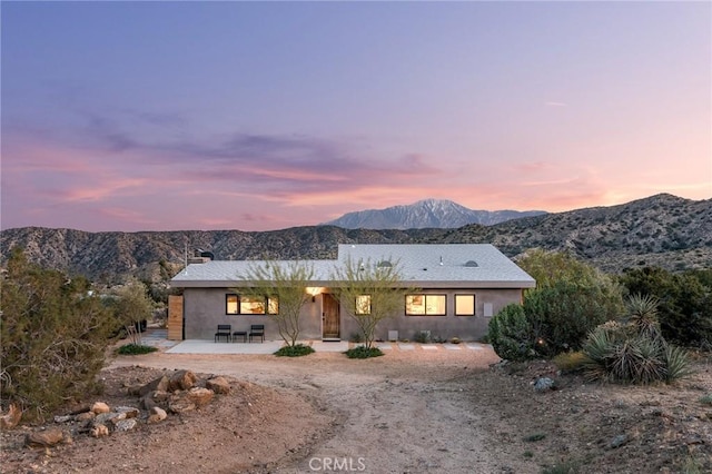 single story home featuring a mountain view, stucco siding, a chimney, and a patio area