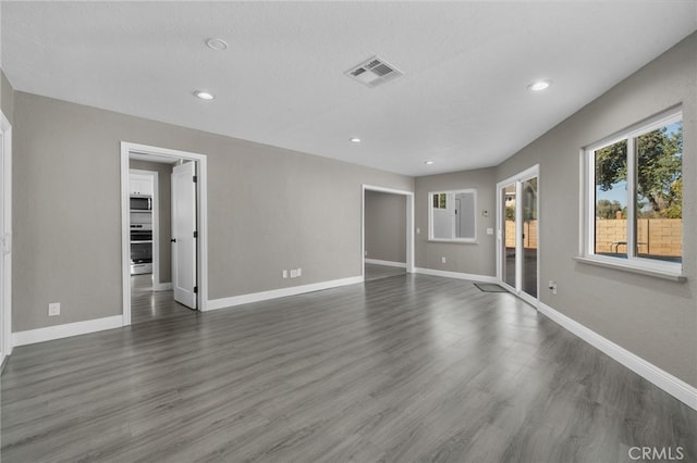 unfurnished living room with recessed lighting, baseboards, visible vents, and dark wood-style floors