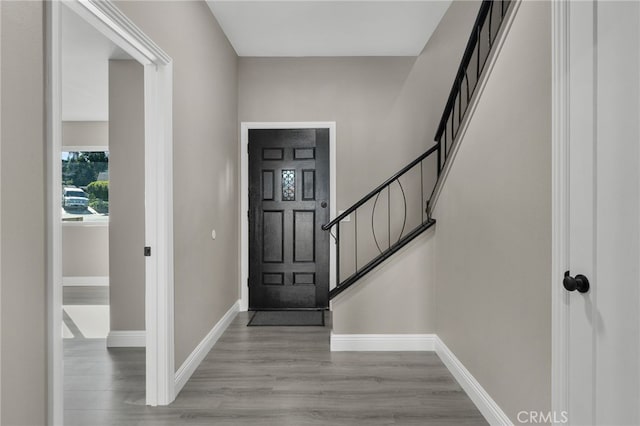 foyer with baseboards, wood finished floors, and stairway